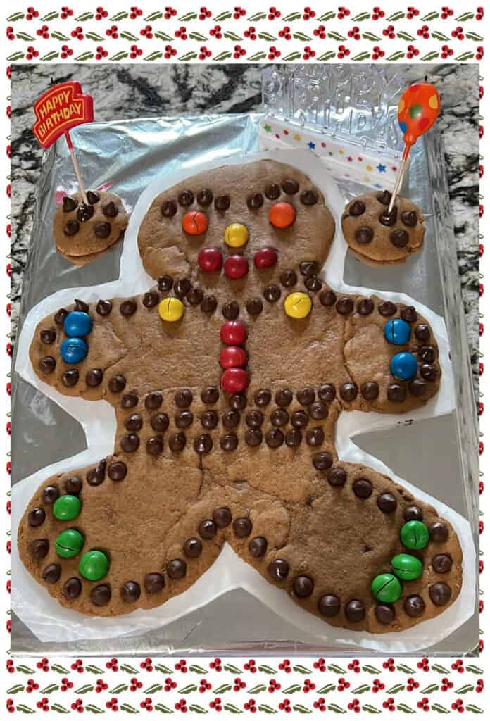 Large gingerbread person cookie decorated with chocolate chips and colourful sweets, baked for a birthday celebration.