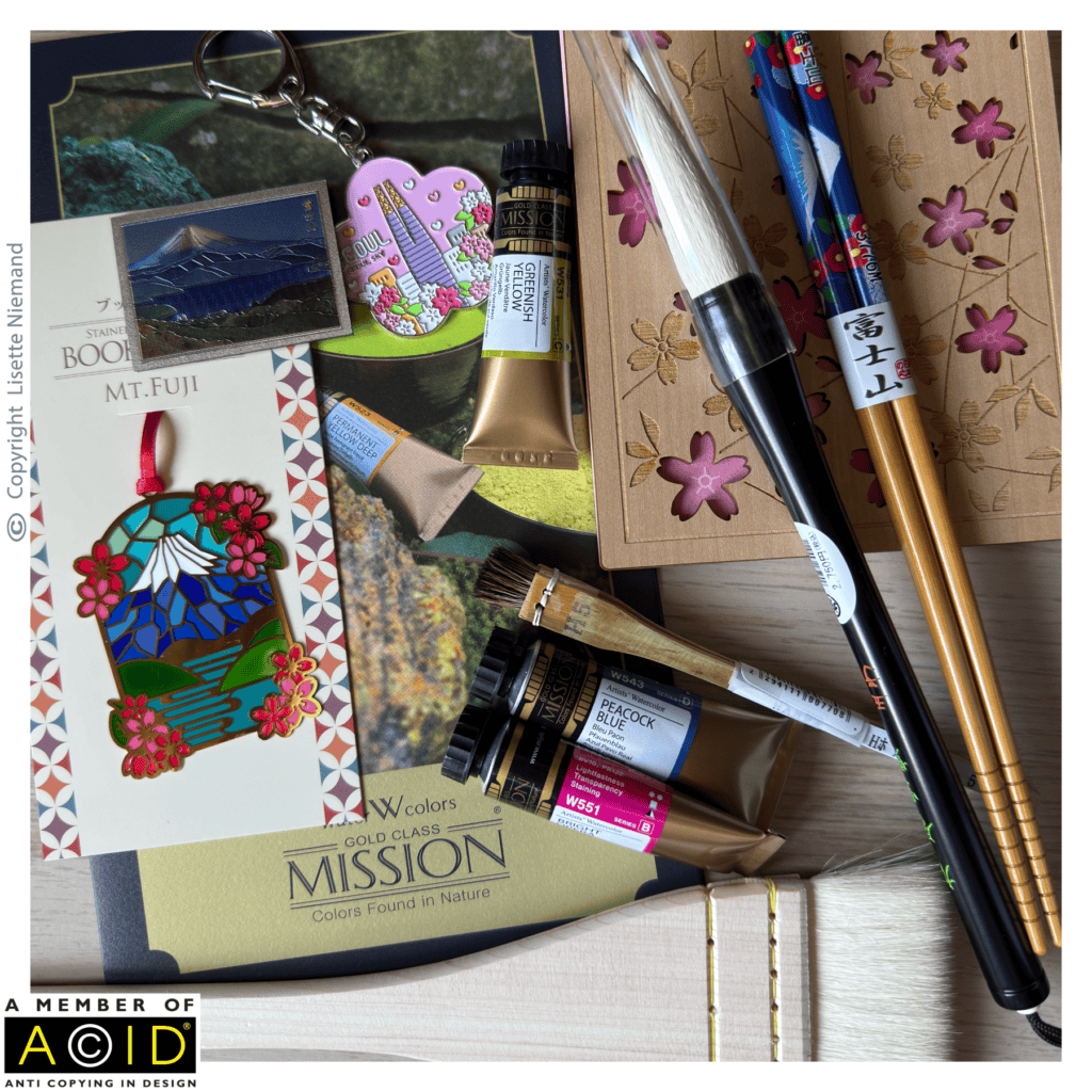 Creative inspiration for surface pattern design showing artist's tools collected during a family trip to South Korea and Japan, including Mijello Mission Gold Class watercolours, traditional Japanese brushes and travel mementos by Lisette Niemand of SassiNiemand.