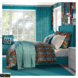 Bedroom interior featuring coordinated African Tapestry bedding, cushions and curtains by Lisette Niemand in peacock blue, magenta and artisan gold tones.
