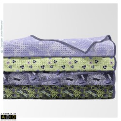 Designs by Lisette Niemand from the Thistle Be Collection shown on folded waffle towels. The coordinated patterns feature sea holly botanicals, dragonflies and complementary floral designs in green, lilac and deep purple tones.