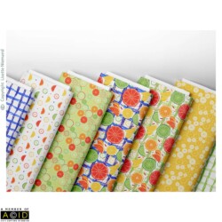 Folded fabric bolts featuring coordinating citrus patterns from the Summer Citrus Mediterranean Market collection by Lisette Niemand, including orange, lemon and lime prints with geometric blenders.