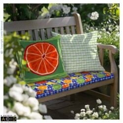 Outdoor bench featuring citrus themed cushions from the Summer Citrus Mediterranean Market Collection by Lisette Niemand, including a bold orange slice design and coordinating green check (painted stripes) pattern.