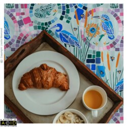 Breakfast tray on duvet cover featuring the Kaleidoscope Pond Life hero pattern in soft green by Lisette Niemand, with herons, frogs, dragonflies and mosaic motifs.